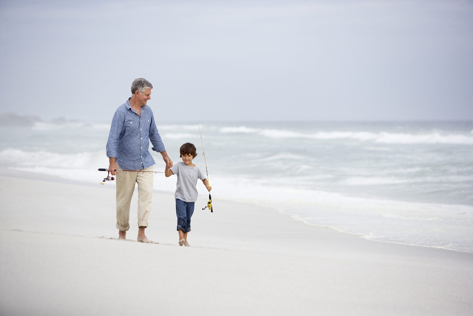 Grandfather & boy fishing on beach